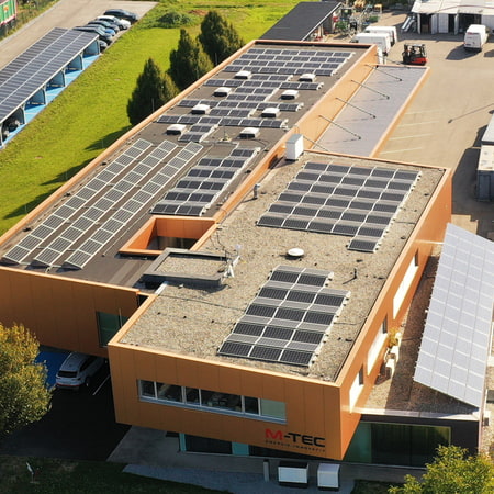 Drohnenaufnahme des Firmengebäudes mit PV-Anlagen am Dach und Solarcarport